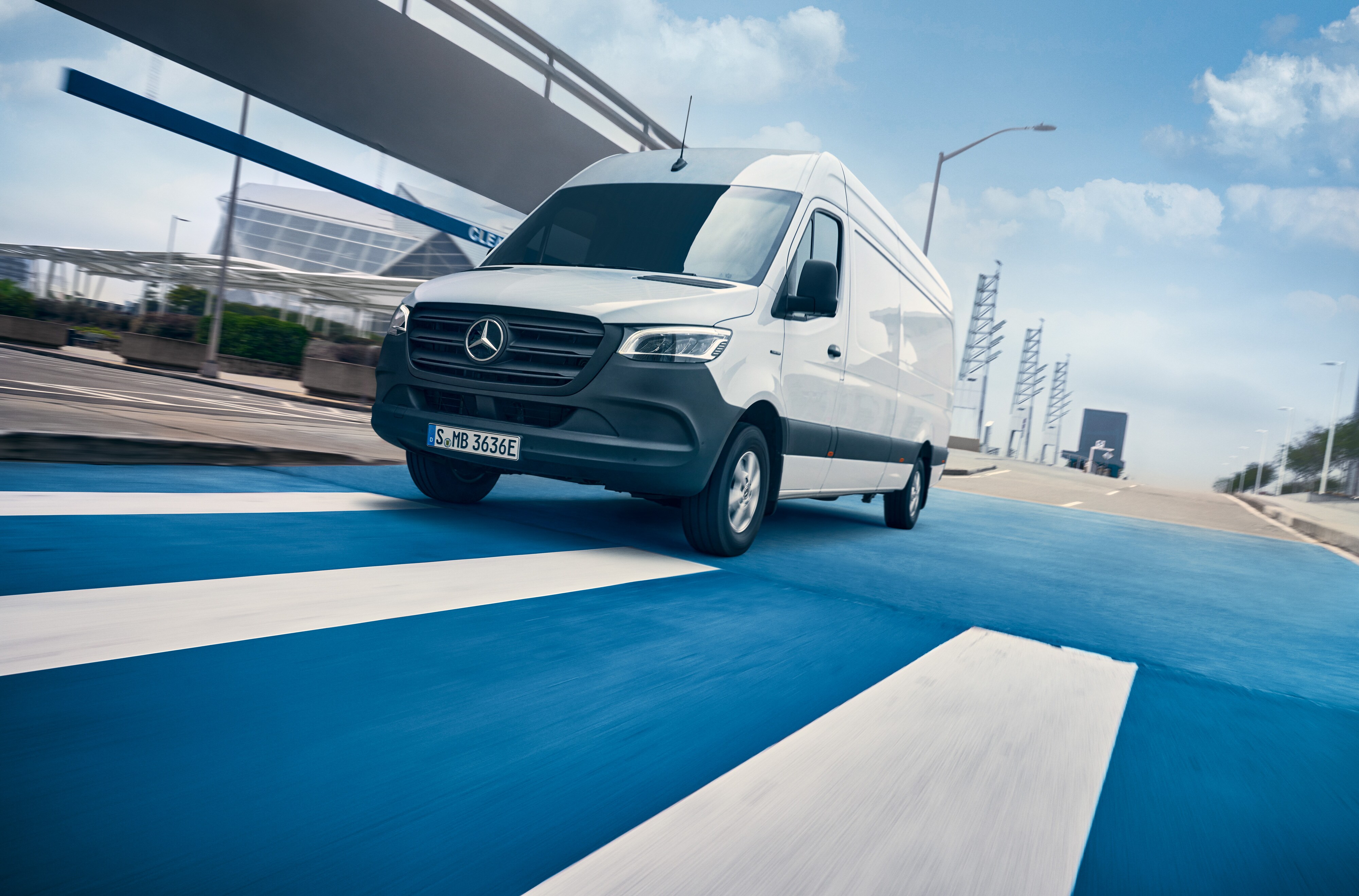 Mercedes-Benz | ServiceCare veículos comerciais ligeiros | Pacote de manutenção Um Mercedes-Benz Sprinter branco circula numa estrada que atravessa uma cidade.